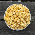 White bowl filled with hot honey popcorn on a wooden surface