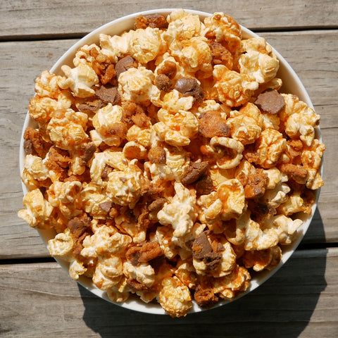 Overhead view of popcorn in a bowl with butterfinger candy bar pieces