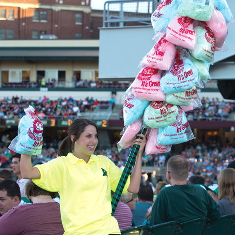 cotton candy vendor carrying a cotton candy pole through a stadium